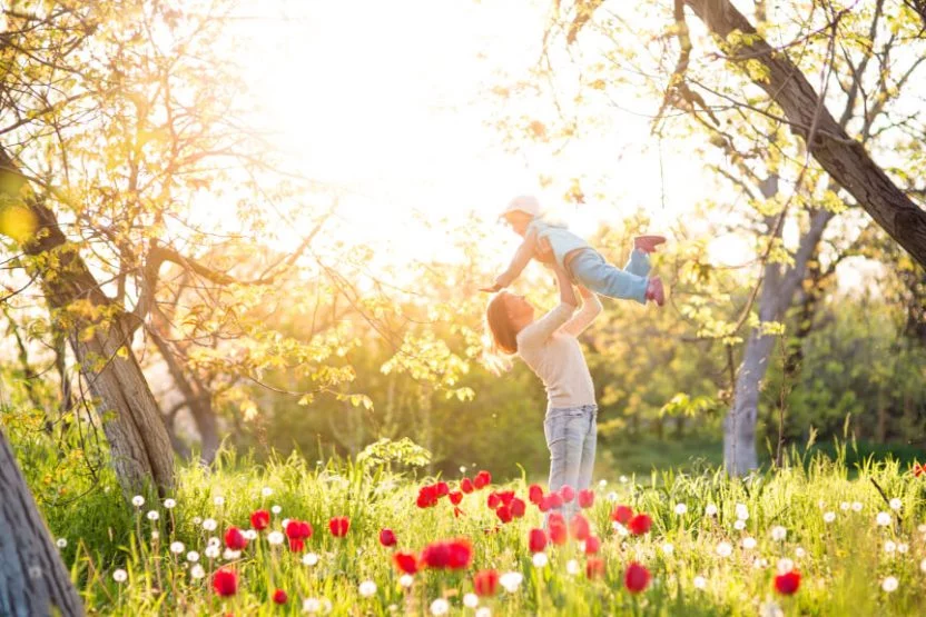 Mother playing with daughter in a field of flowers